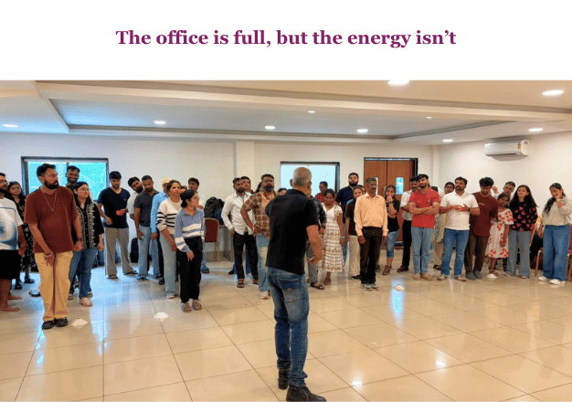 The office is full, but the energy isn’t — a facilitator addressing a team in an office hall