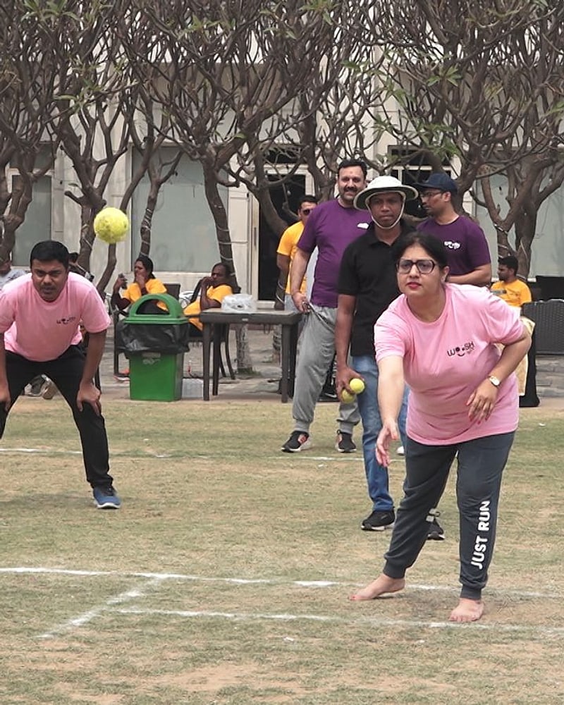 A Woosh Biz lawn game in play on a resort lawn, with the resort's verandah, trees and garden seating behind