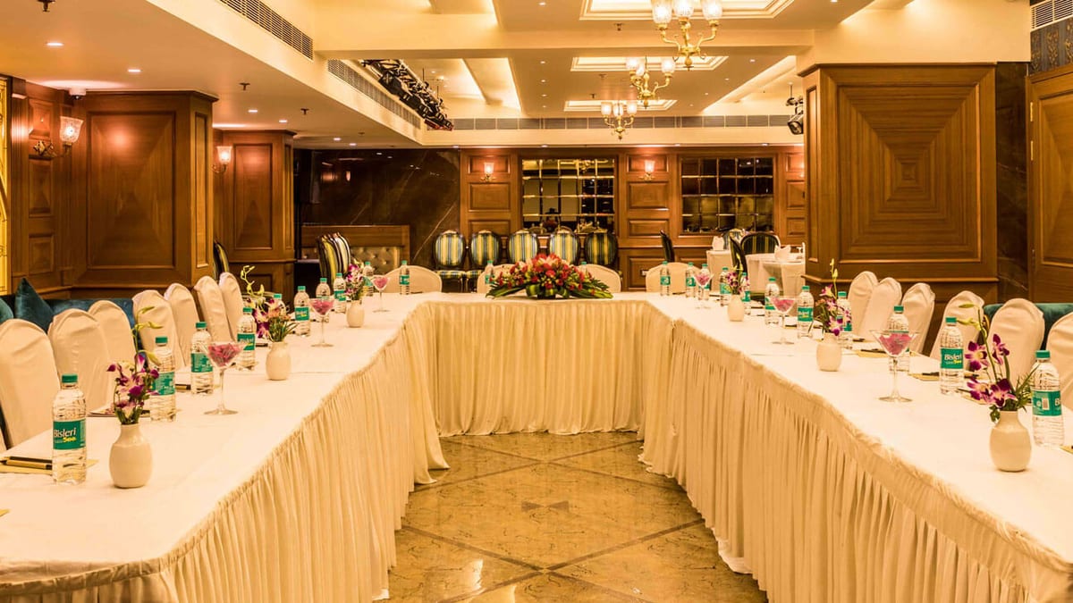 Banquet hall laid out in a U-shaped conference setting with flowers on the tables